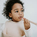 Girl eats strawberries using Boo Chew silicone giraffe spoon in oat colour